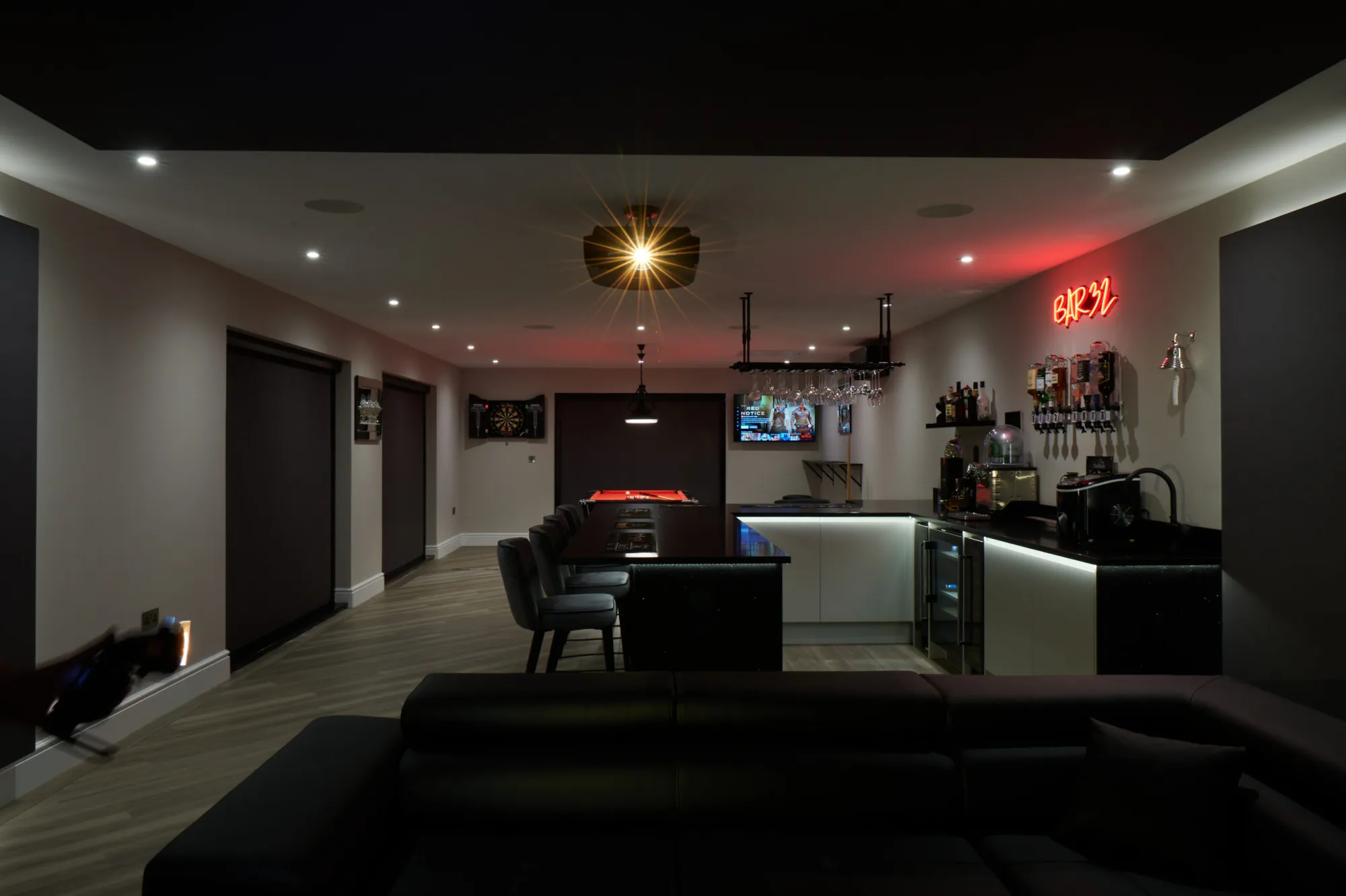Wide lounge bar with feature lighting and wall screen, commercial AV Kent