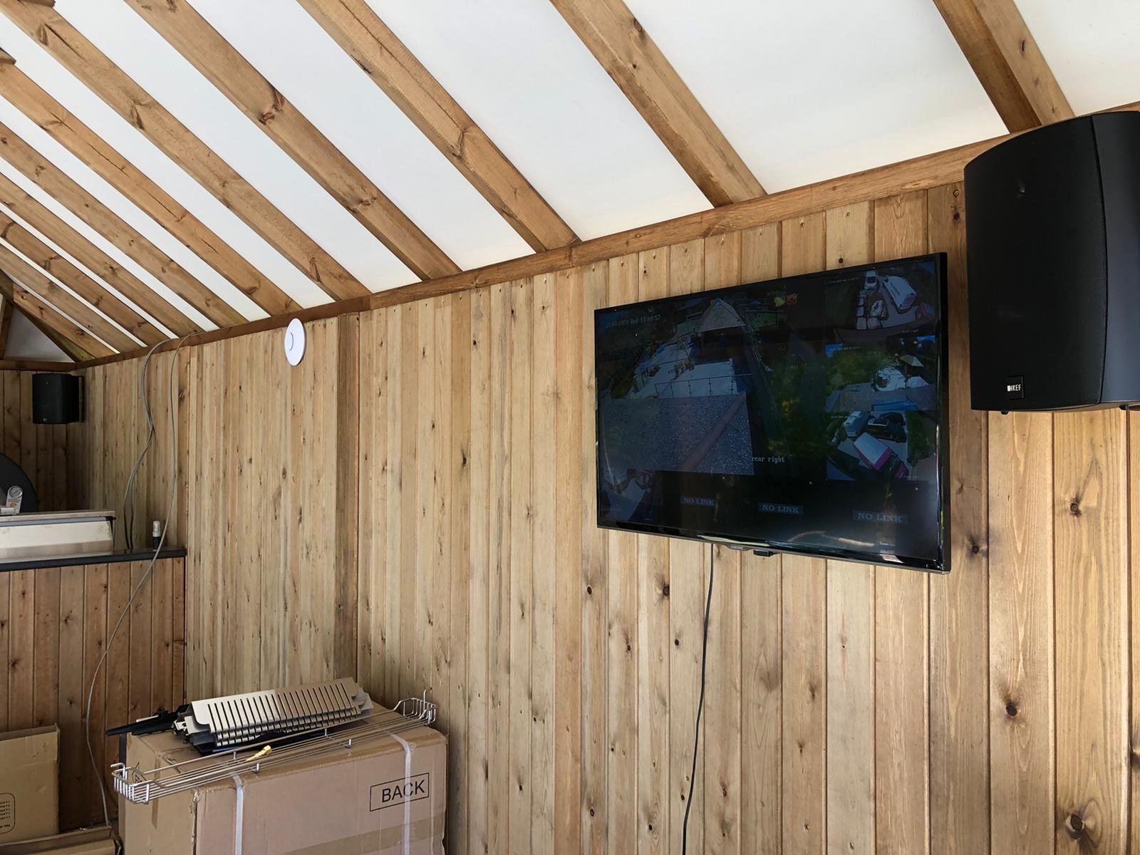 Timber-clad garden office with wall-mounted TV and speaker, Surrey office AV installation