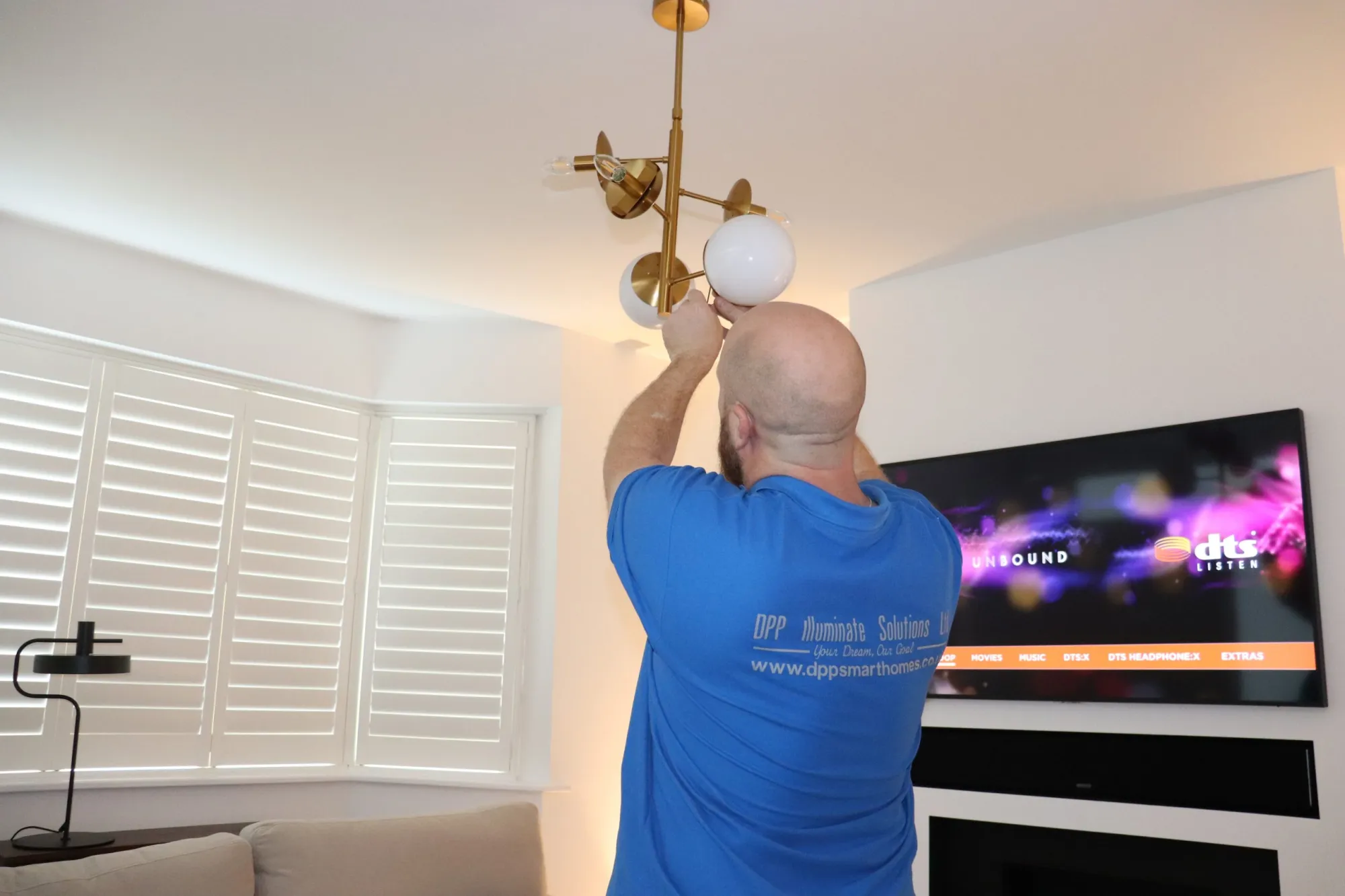 Engineer mounting a display screen on a wall for an Essex shop